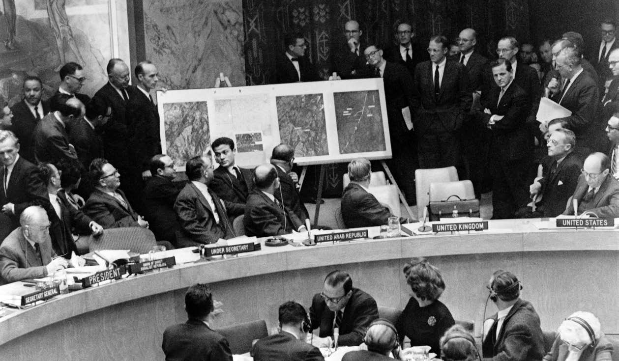 U.S. Ambassador to the United Nations Adlai Stevenson, seated on right, describes location of missile sites in Cuba using aerial photographs during United Nations Security Council meeting in New York City, October 25, 1962 (Everett Collection/Alamy)